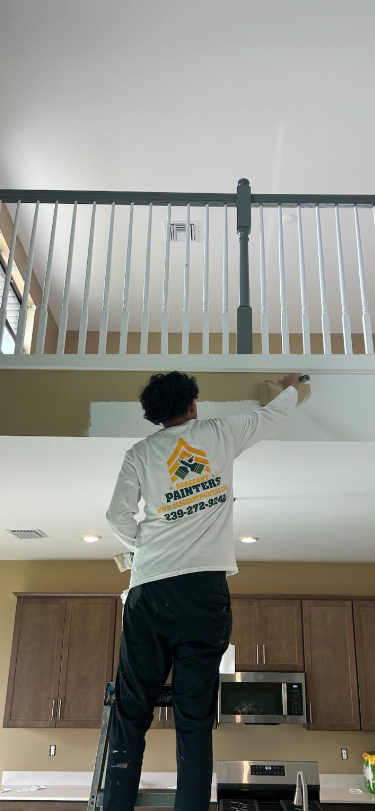 Sergeant Painters crew member in company shirt cutting in a ceiling by hand