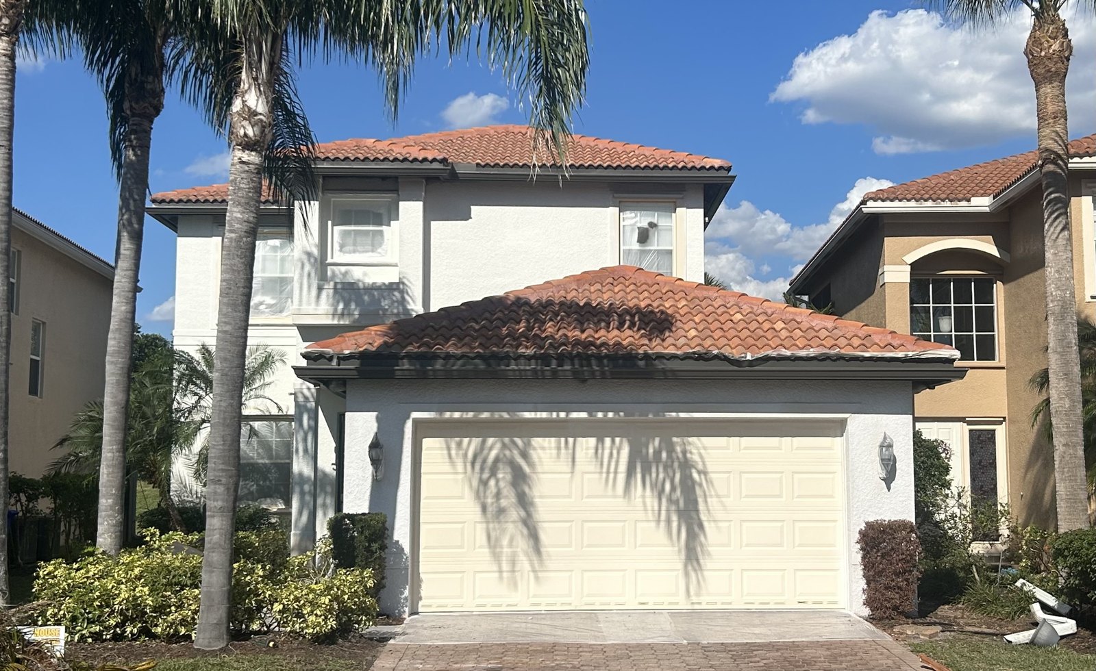 Freshly repainted white Mediterranean-style home with tile roof
